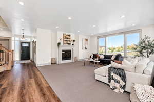 Living area featuring stairs, recessed lighting, a glass covered fireplace, and wood finished floors