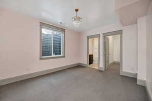Unfurnished bedroom featuring carpet floors, a chandelier, and ensuite bath