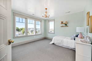 Carpeted bedroom featuring baseboards and a chandelier