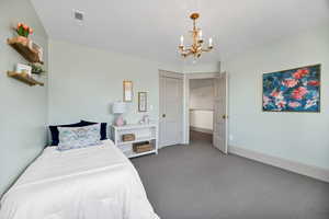 Carpeted bedroom with a chandelier and baseboards