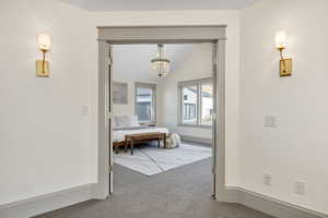 Carpeted bedroom featuring vaulted ceiling and a chandelier