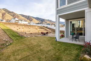 View of yard with a patio, a mountain view, and a balcony