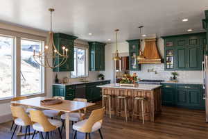 Kitchen featuring green cabinetry, glass insert cabinets, light stone counters, decorative backsplash, and a kitchen island