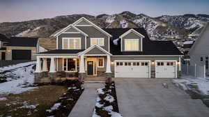 View of front of house featuring stone siding, a porch, a garage, a mountain view, and concrete driveway