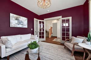 Living room featuring stairs, dark wood-style floors, and a chandelier