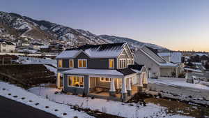 Snow covered rear of property with covered porch, a residential view, and a mountain view