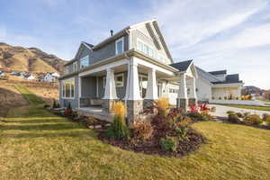 View of home's exterior with covered porch, stone siding, a yard, and a garage