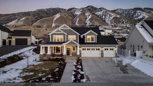 View of front of home featuring a porch, concrete driveway, stone siding, and a mountain view