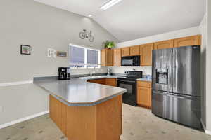 Kitchen featuring black appliances, a peninsula, and vaulted ceiling