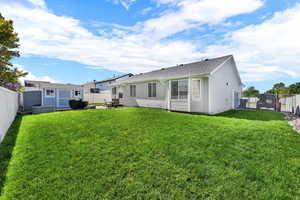 Back of house with a fenced backyard, a gate, a patio, roof with shingles, and an outbuilding