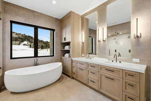 Full bathroom featuring tile walls, double vanity, a soaking tub, a stall shower, and light tile patterned flooring