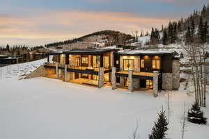 Snow covered house with stone siding and a mountain view