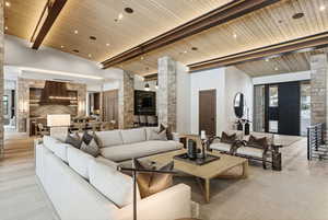 Living room with a wood ceiling with exposed beams, a towering ceiling, and light wood finished floors