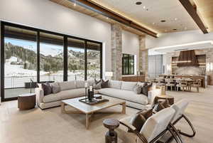 Living room with a wood ceiling with exposed beams, light wood finished floors, a towering ceiling, and a mountain view