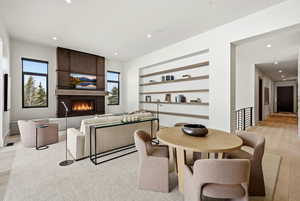 Dining space with light wood-style flooring, a large fireplace, built in features, and recessed lighting