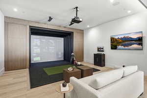 Home theater room featuring golf simulator, light wood finished floors, and recessed lighting