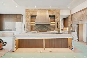 Kitchen featuring recessed lighting, brown cabinetry, custom exhaust hood, and a kitchen breakfast bar