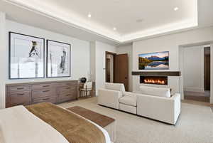 Bedroom featuring a lit fireplace, recessed lighting, and a tray ceiling