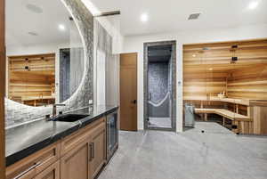 Kitchen featuring a relaxing sauna, brown cabinets, wine cooler, and dark stone countertops