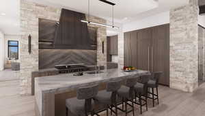 Kitchen with modern cabinets, a breakfast bar, hanging light fixtures, a center island with sink, and custom exhaust hood