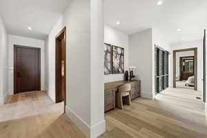 Hallway with an office area, light wood-style floors, and recessed lighting