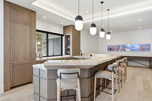 Kitchen with pendant lighting, light stone countertops, light wood-style flooring, brown cabinetry, and recessed lighting