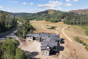 Aerial view of property and surrounding area with a forest and mountains