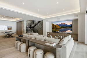 Cinema with a raised ceiling, light wood-style floors, and recessed lighting