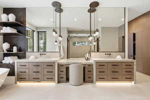 Full bath featuring two vanities, decorative backsplash, a freestanding bath, and recessed lighting