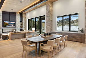 Dining space with a towering ceiling, a wooden ceiling with exposed beams, and light wood finished floors