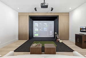 Game room with golf simulator and light wood-style floors