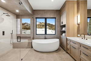 Bathroom featuring tile walls, a freestanding tub, vanity, a stall shower, and a mountain view