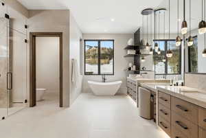 Bathroom with two vanities, a freestanding bath, a stall shower, and healthy amount of natural light
