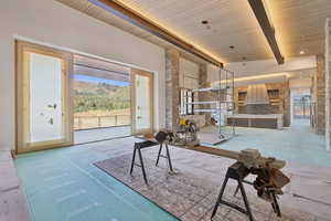 Living area with healthy amount of natural light and a wood ceiling with exposed beams