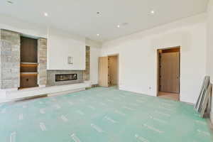 Unfurnished living room featuring carpet, a glass covered fireplace, and recessed lighting