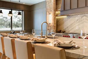 Kitchen featuring light stone counters, decorative light fixtures, custom exhaust hood, and designer stove