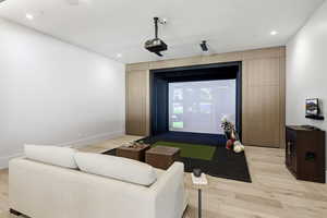 Living room featuring golf simulator, light wood-style floors, and recessed lighting