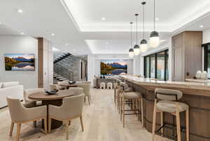 Dining space with a tray ceiling, light wood-type flooring, stairway, and recessed lighting