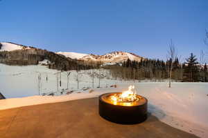 Snow covered patio featuring an outdoor fire pit and a mountain view