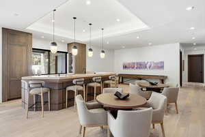 Dining room featuring light wood-style floors, recessed lighting, and a tray ceiling