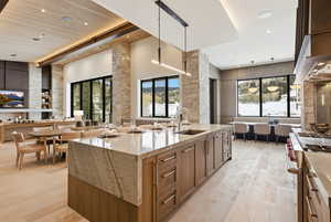 Kitchen with light stone counters, pendant lighting, range with two ovens, open floor plan, and a towering ceiling