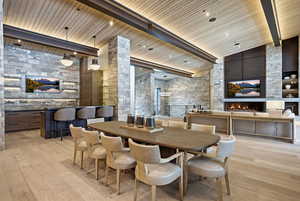 Dining area with a fireplace, light wood-style floors, high vaulted ceiling, and a wood ceiling with exposed beams