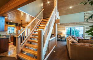 Staircase with wood ceiling, a high ceiling, rustic walls, carpet, and recessed lighting