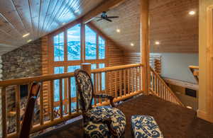 Sitting room with log walls, a mountain view, a ceiling fan, high vaulted ceiling, and a wooden ceiling with exposed beams