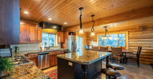 Kitchen featuring plenty of natural light, pendant lighting, brown cabinetry, stainless steel appliances, and wooden ceiling