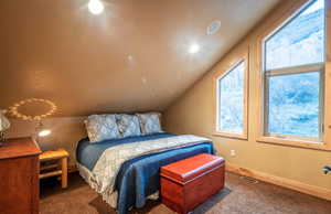 Carpeted bedroom featuring baseboards and vaulted ceiling