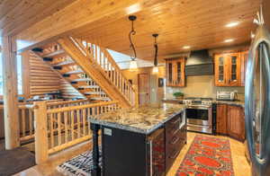 Kitchen with wood ceiling, glass insert cabinets, pendant lighting, custom exhaust hood, and appliances with stainless steel finishes