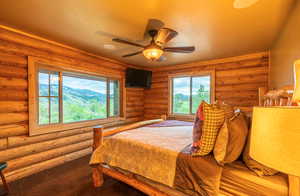 Carpeted bedroom featuring a textured ceiling, a ceiling fan, and log walls