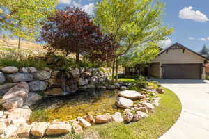 View of front facade featuring a small pond, driveway, and an attached garage