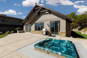 Back of property featuring stone siding and a patio